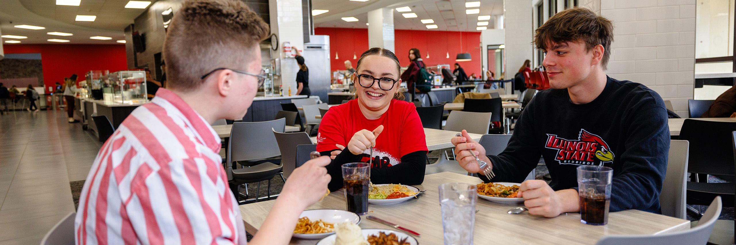 Student eats breakfast while looking at his phone.